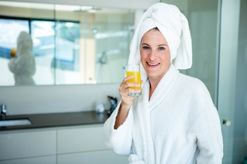 woman wearing a dressing gown drinking a glass of juice