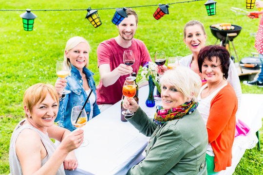 Freunde und Nachbarn an Tafel feiern Gartenparty und sto&szlig;en an