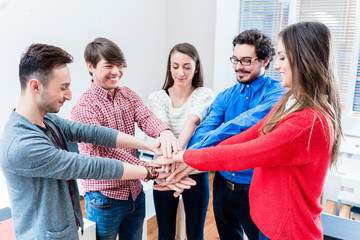 Studenten in Hochschule halten zusammen und stapeln Hände als Team