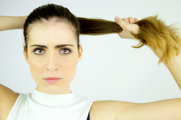 Beautiful female model pulling long hair in ponytail looking serious camera closeup