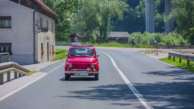 Red car passing a house