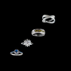 Collection of rings with colorful gems on black background.
