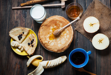 pancakes with honey and ingredients on wooden background