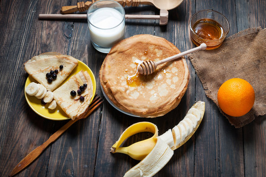 pancakes with honey and ingredients on wooden background