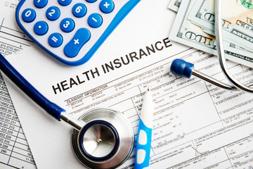 Health insurance application form with banknote and stethoscope