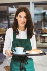 Waitress holding tray with coffee and croissant