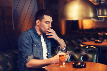 man drinking beer and smoking cigarette at bar