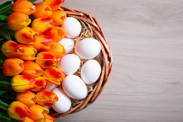 Easter concept - top view of white eggs and tulips in basket on