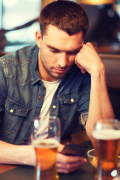 man with smartphone and beer texting at bar
