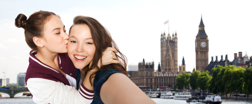 happy teenage girls taking selfie in london