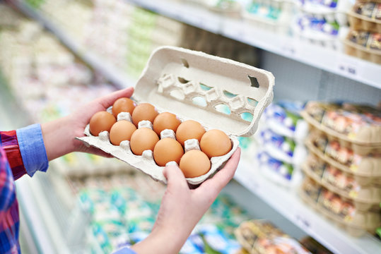 In hands of woman packing eggs in supermarket