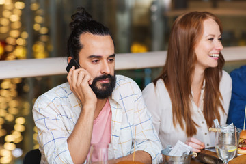 man with smartphone and friends at restaurant