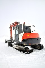 Tracklaying excavator at top of snow mountain