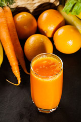 Glass of fruit juice with orange, carrots and banana