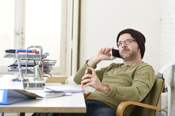 young attractive hipster businessman working from home office with mobile phone