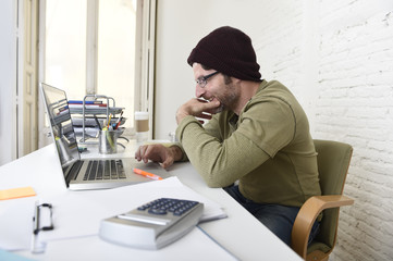 young attractive hipster businessman working with computer in modern home office