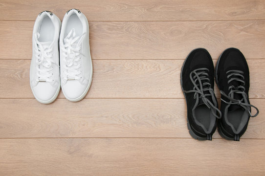 Two pairs of sneakers on a wooden background,  black VS white concept