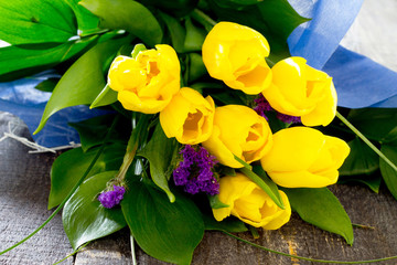 Bouquet of yellow tulips in a gift on a dark wooden table