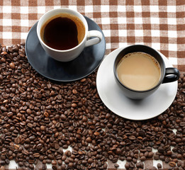  Two coffee cups and coffee beans on a checkered cloth