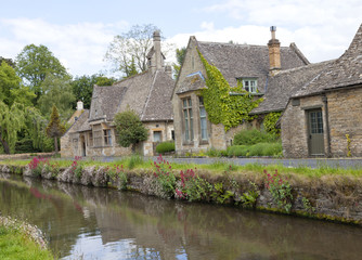Fototapeta na wymiar English stone cottages in the traditional Cotswold style along banks of river Eye with wild flowers