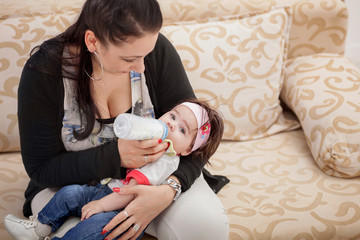 mother feeding her little baby girl from the milkbottle