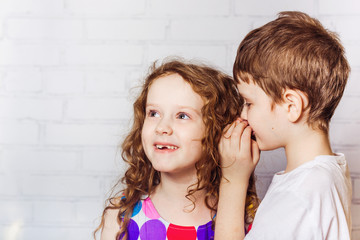 Little boy and girl whispers in school.