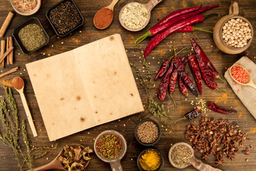 colorful spices and herbs on wooden table. Cutlery silhouette. Asian Indian cuisine ingredients. Healthy vegetarian food. Recipe, menu, mock up, cooking.