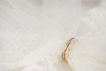Closeup of a white wedding veil put hrough a couple of golden rings