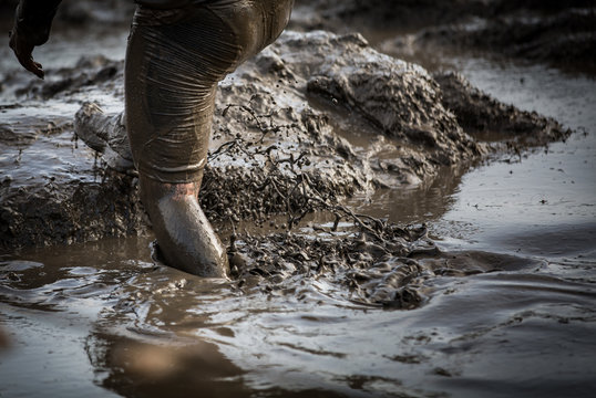 Deep muddy water with feet splashing and climbing out of the mud in a race