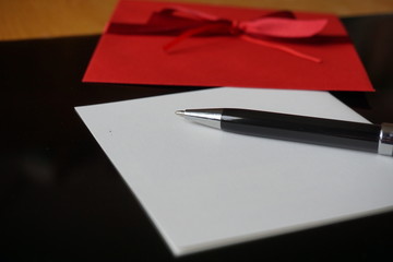 Black pen writing announcement letter with the decorated red envelope 