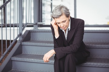 Upset businesswoman sitting on steps