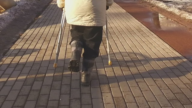 Mature woman on crutches in a city park