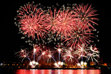 Firework over city at night with reflection in water