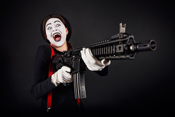 Fototapeta na wymiar Crazy smiling mime with gun/Crazy smiling girl mime with rifle in hands on black background