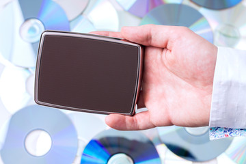 Man's hand with portable disk over CD's background. Concept of data storage.