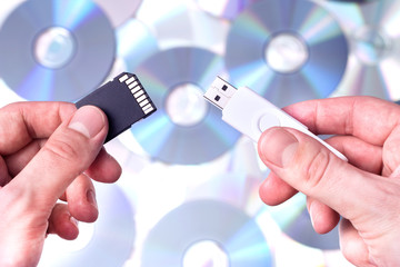 Obraz premium Man's hands with SD card and pendrive over CD's background. Conc