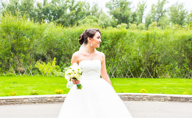 Fototapeta na wymiar Beautiful bride girl in wedding dress with bouquet of flowers, outdoors portrait