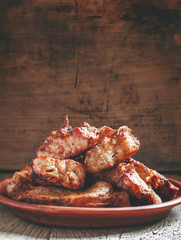 Pieces of shish kebab, grilled, on a clay dish, old wooden backg