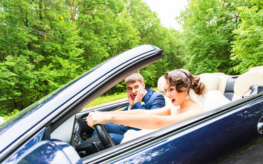 Beautiful young couple bride and groom posing in cabriolet 