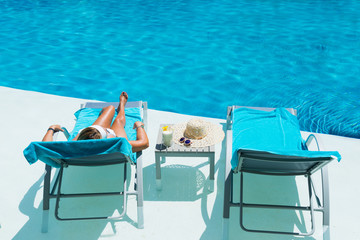 Woman  relaxing at the pool with pina colada cocktail