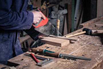 Carpenter Sawing a Piece of Wood with a Handsaw