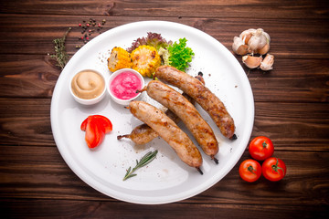 Grilled sausages with vegetables and seasoning on wood