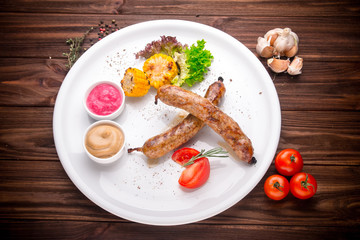 Grilled sausages with vegetables and seasoning on wood
