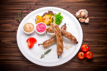 Grilled sausages with vegetables and seasoning on wood