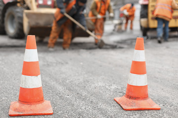 road workers repair the road,  cones in  foreground
