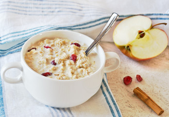 Oatmeal porridge with apples and cinnamon on marble table