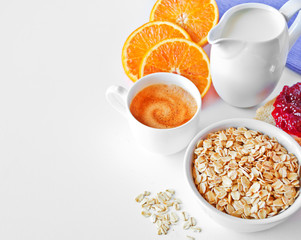 Breakfast - milk, oatmeal,sliced of orange on white.