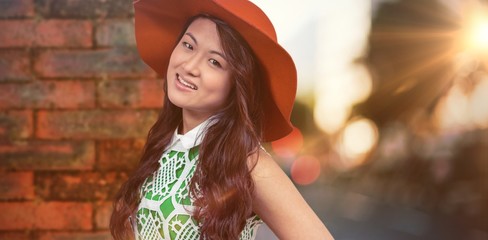 Composite image of asian woman with hat posing for camera