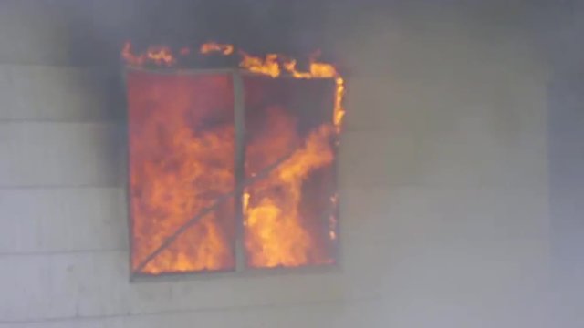 Window burns with a fury coming from a burning house 
