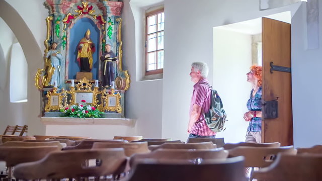 Old man and woman walk into the church and see the sculptures 